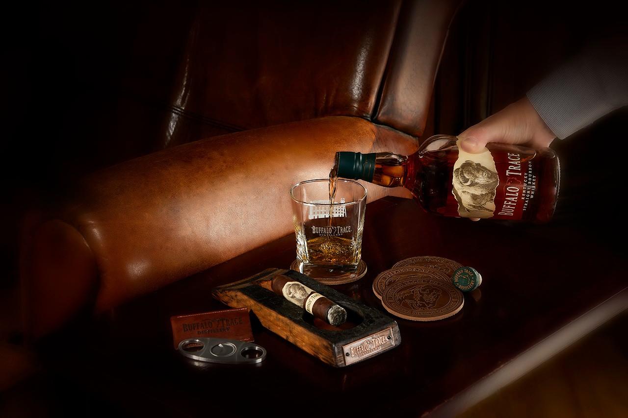 Man pouring bottle of Buffalo Trace with cigar in ash tray